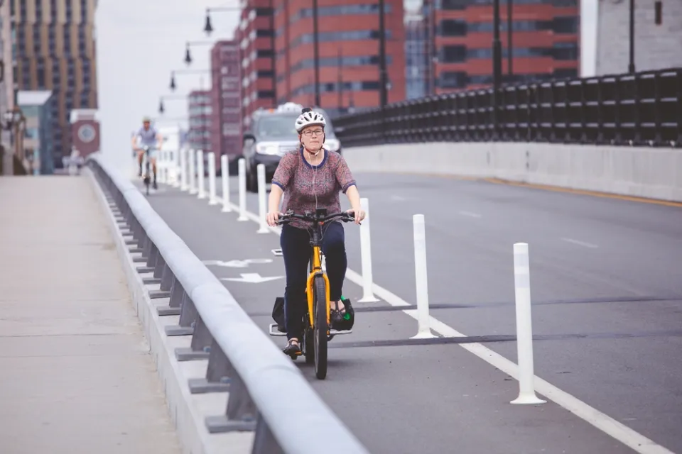 Woman on bicycle in protected bike lane on Boston bridge
